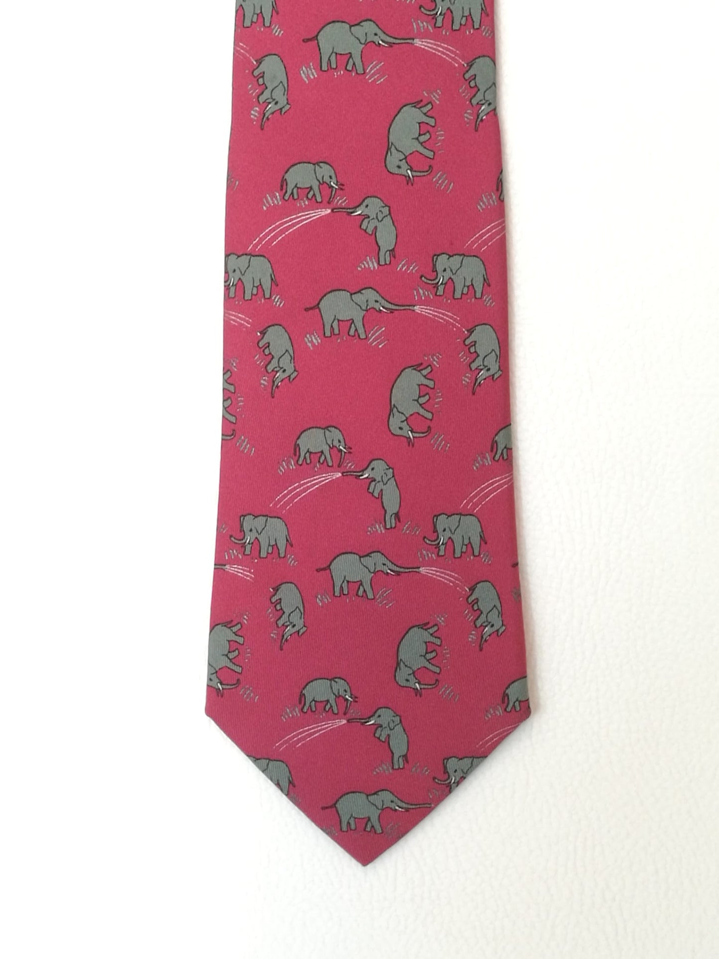Cravatta Hermès con sfondo rosa con elefanti grigi.